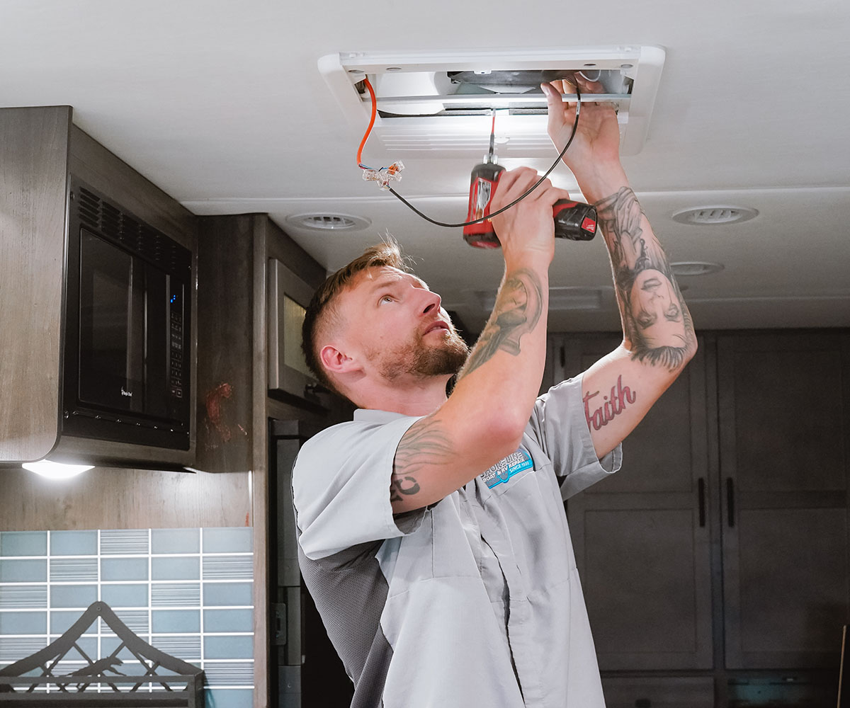 Josh working on an AC vent inside an RV